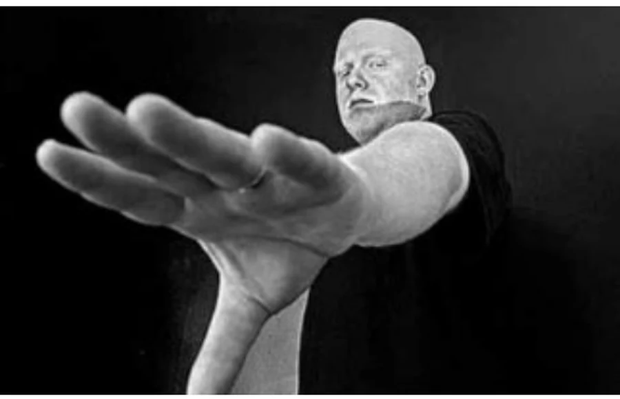 Black and white photograph of a man’s head above a large outstretched hand