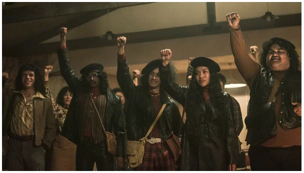 Cast of the series The Panthers with fists raised in a hall
