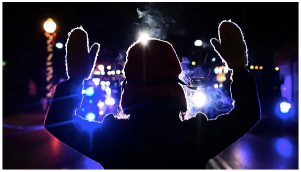 Silhouetted hands raised at a night-time protest, lit blue and white